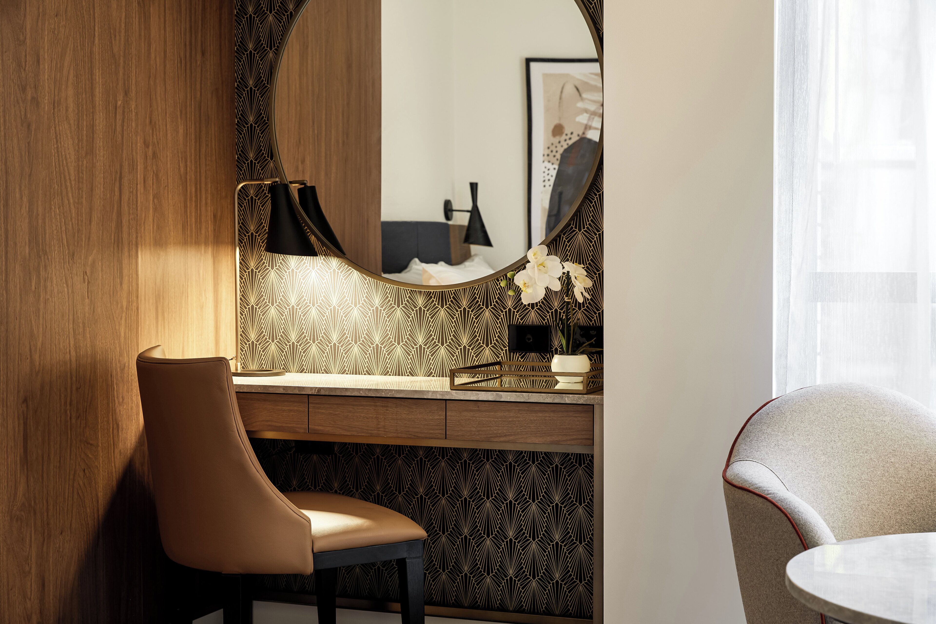 A modern bathroom with a wooden vanity, a mirror, and a chair.