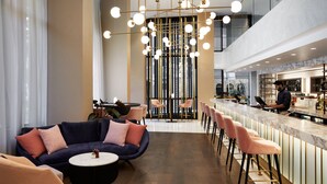 A modern bar area with a bar counter, seating, and a decorative light fixture.