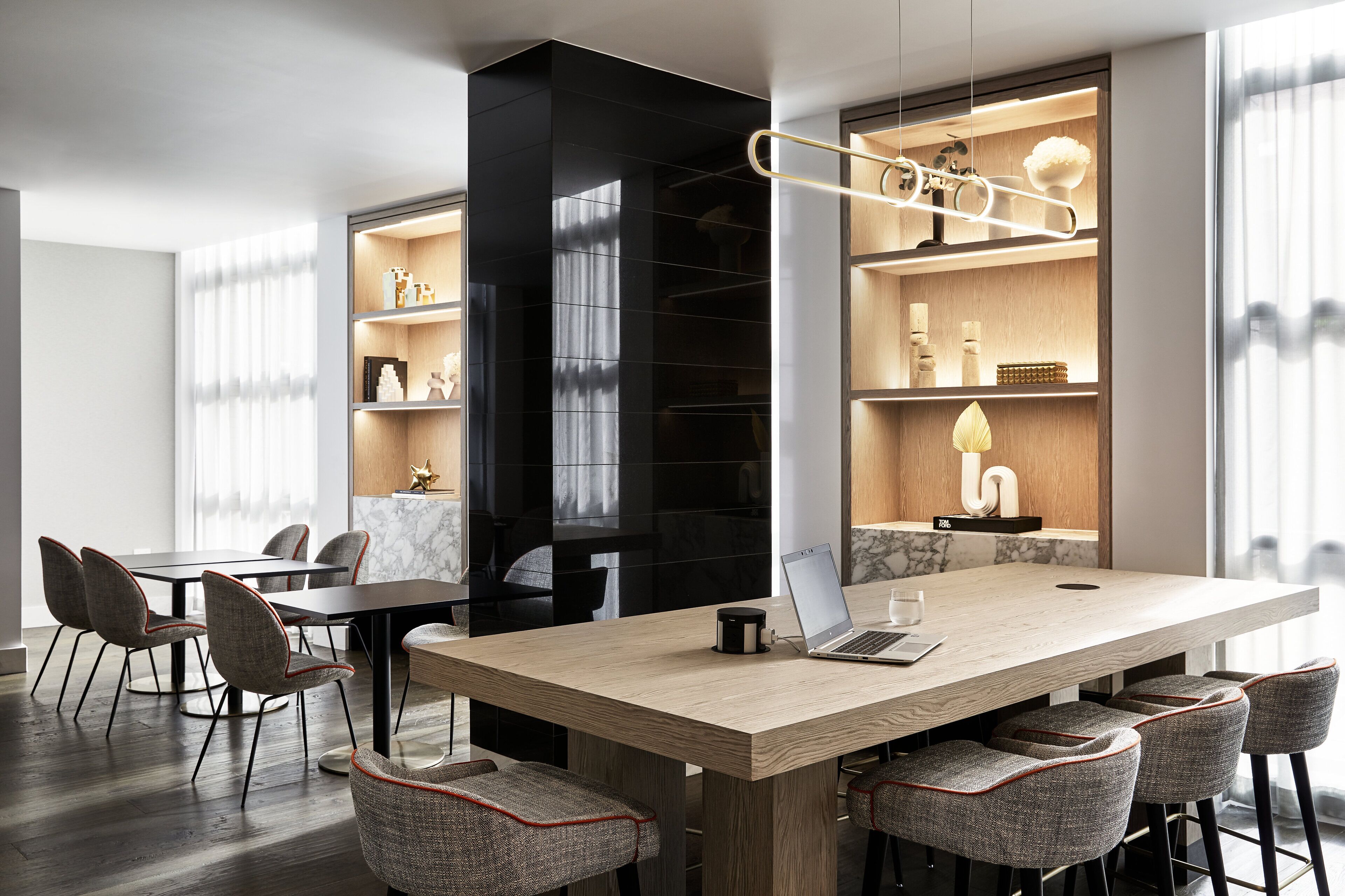 A modern conference room with a large table, chairs, and built-in shelving with decorative items.