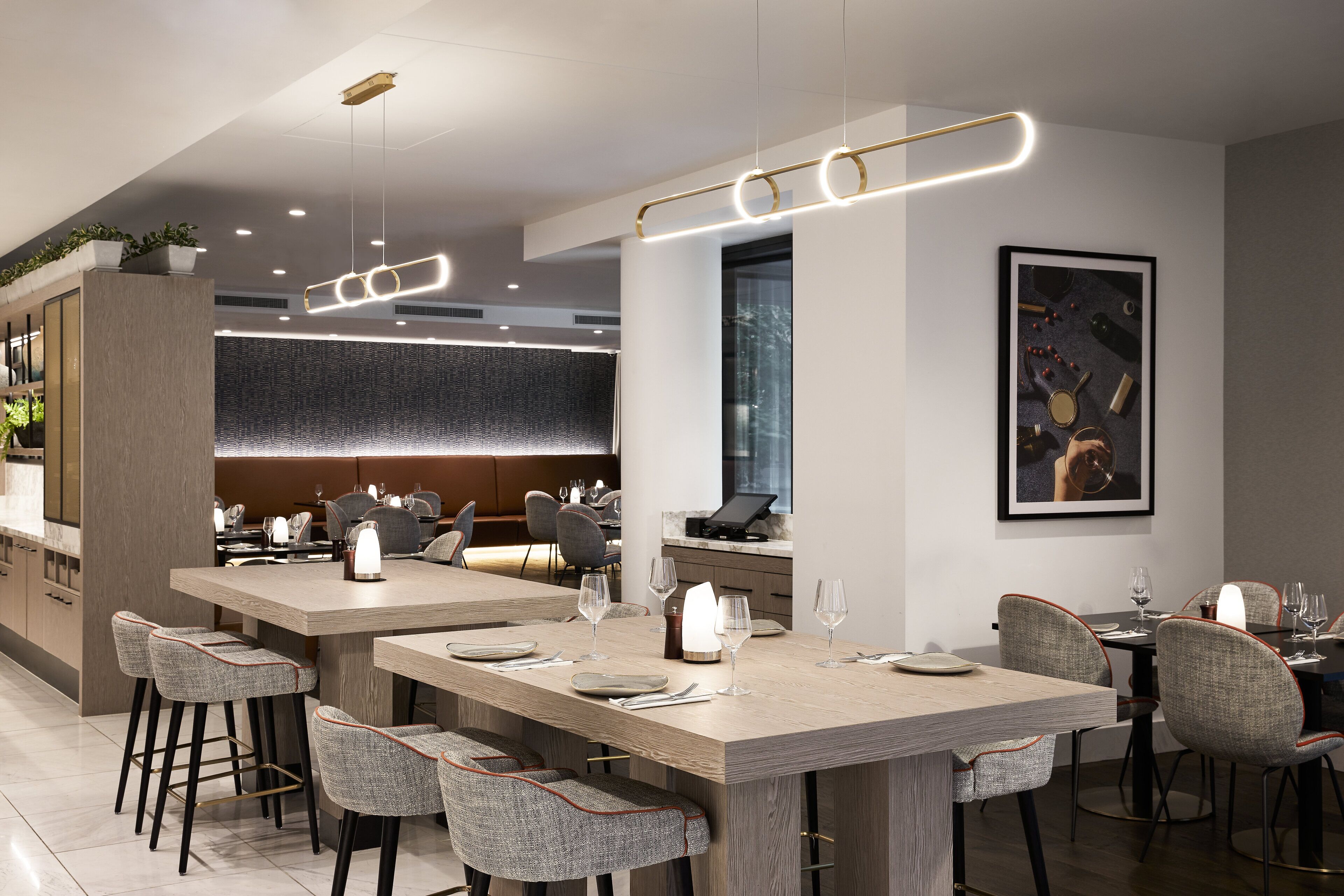 Un comedor moderno con una larga mesa de madera, taburetes de bar e iluminación colgante.