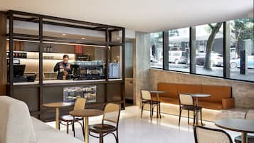 A modern cafe with a bar area, seating, and large windows offering a street view.