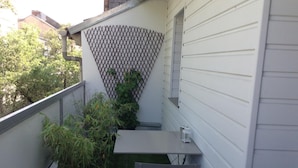 A small balcony with a table and two chairs, surrounded by potted plants and a lattice fence. - Chambre Venus (Vichy)