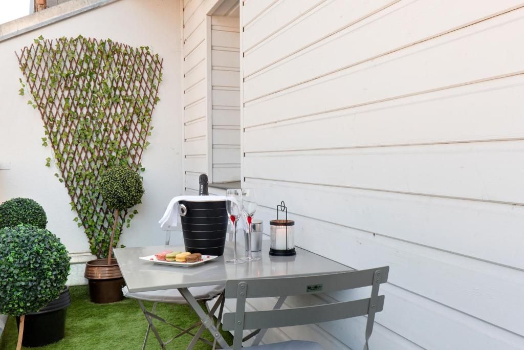 A patio with a table set for two, a decorative lattice, and a small potted plant.