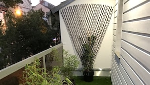 A small balcony with artificial grass, potted plants, and a lattice fence. - Chambre Venus (Vichy)
