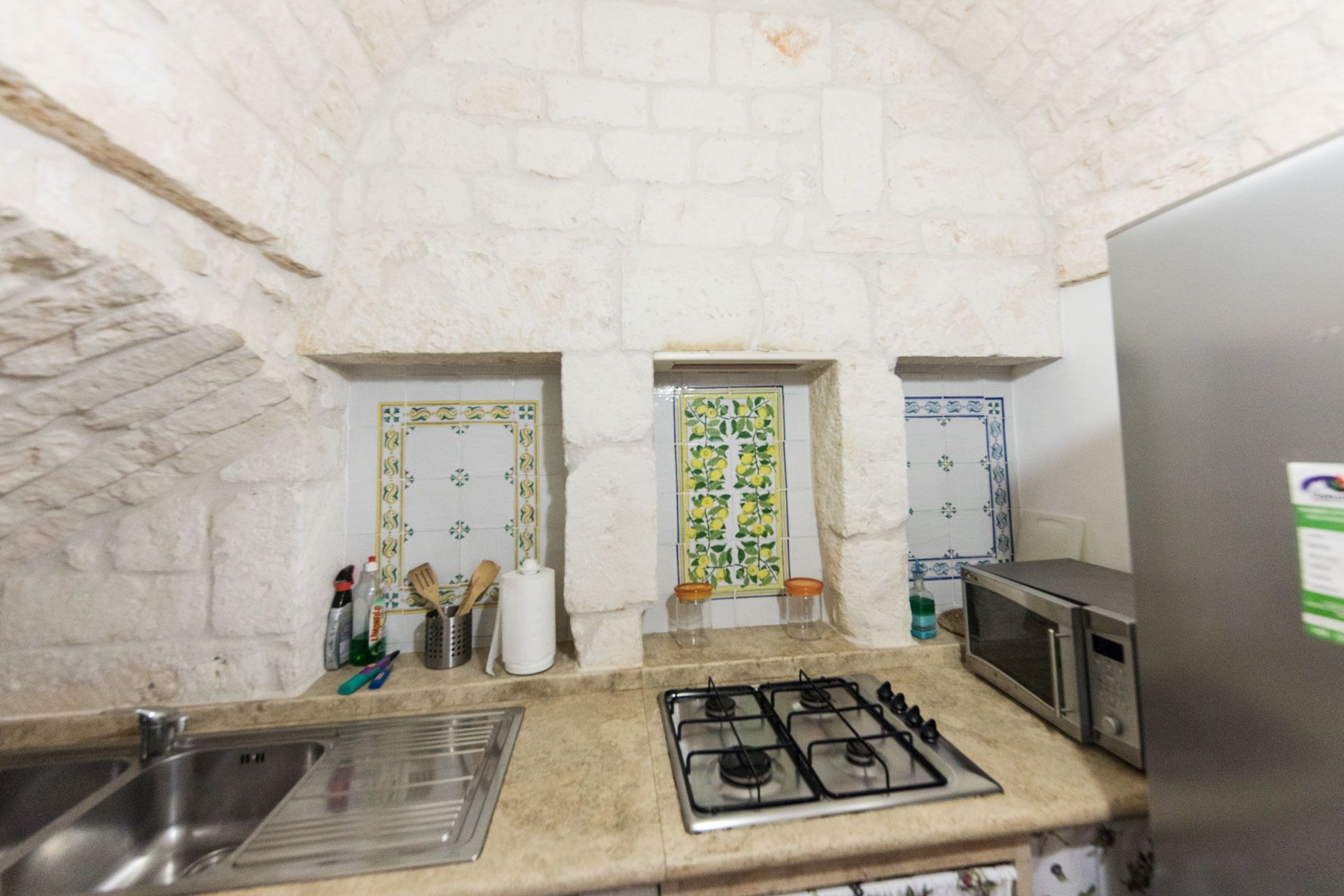 Una cocina con estufa a gas, un fregadero, un microondas y azulejos decorativos.