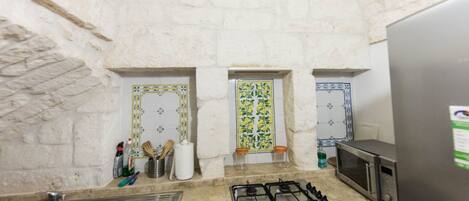 Una cocina con estufa a gas, un fregadero, un microondas y azulejos decorativos.