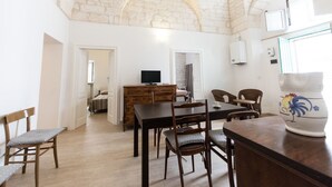 A dining area with a stone ceiling, wooden furniture, and a television in the background. - A casa di Francesca (Ostuni)