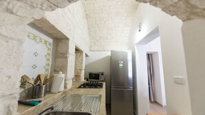 A kitchen with a stainless steel refrigerator, a microwave, and a gas stove. There is a sink and a countertop with various kitchen items. - A casa di Francesca (Ostuni)