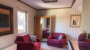 A living room with two red sofas, a wooden coffee table, and a mirror reflecting the room. - Demosan Hotel Hilden (Hilden)