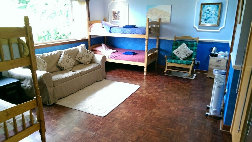 A room with a bunk bed, a sofa, a chair, and a radiator.