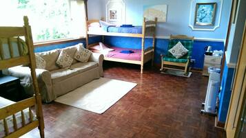 A room with a bunk bed, a sofa, a chair, and a radiator.