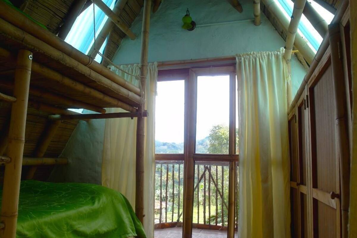 Ein Zimmer mit Etagenbett, großem Fenster mit Vorhängen und Blick ins Freie.