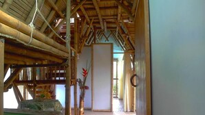 A bamboo structure with a bed and a table with flowers. - Ecoturismo La Nohelia (Jericó)