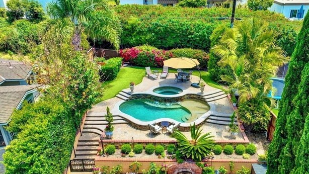 Un jardin aménagé avec une piscine, un espace salon extérieur et une petite cascade décorative.