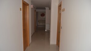 A narrow hallway with wooden doors on either side, leading to a living area with a sofa and a radiator.
