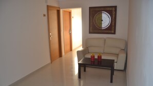 A hallway with a beige sofa, a small table, and two red bottles.
