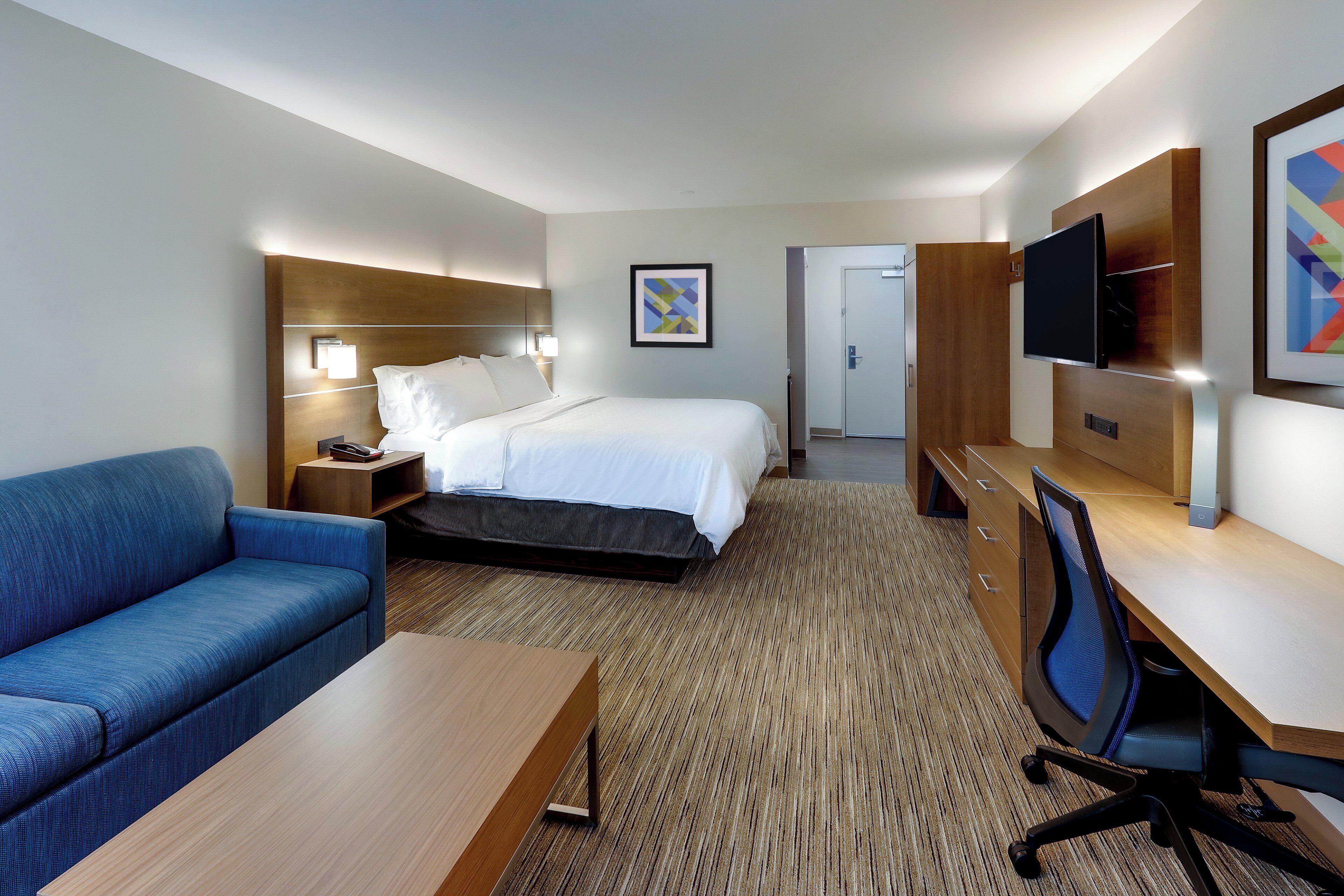 Ein Hotelzimmer mit Bett, Sofa, Schreibtisch und Fernseher.