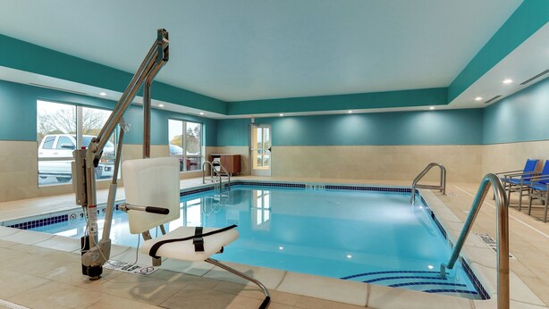 An indoor swimming pool with a lifeguard chair, poolside chairs, and a clear view of the outside through large windows. - Holiday Inn Express & Suites Middletown - Goshen by IHG (Middletown)