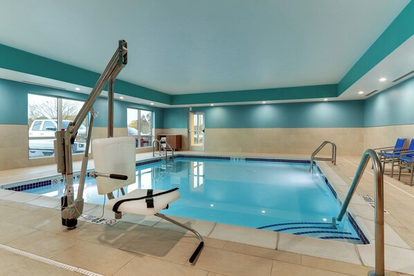 An indoor swimming pool with a lifeguard chair, poolside chairs, and a clear view of the outside through large windows. - Holiday Inn Express & Suites Middletown - Goshen by IHG (Middletown)