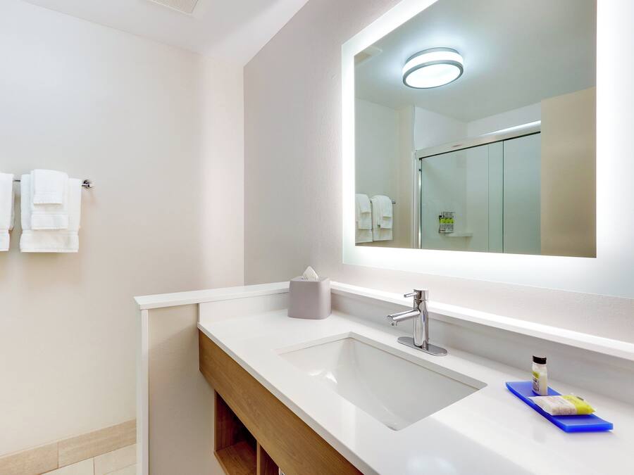 A modern bathroom with a white sink, a mirror, and a towel rack.