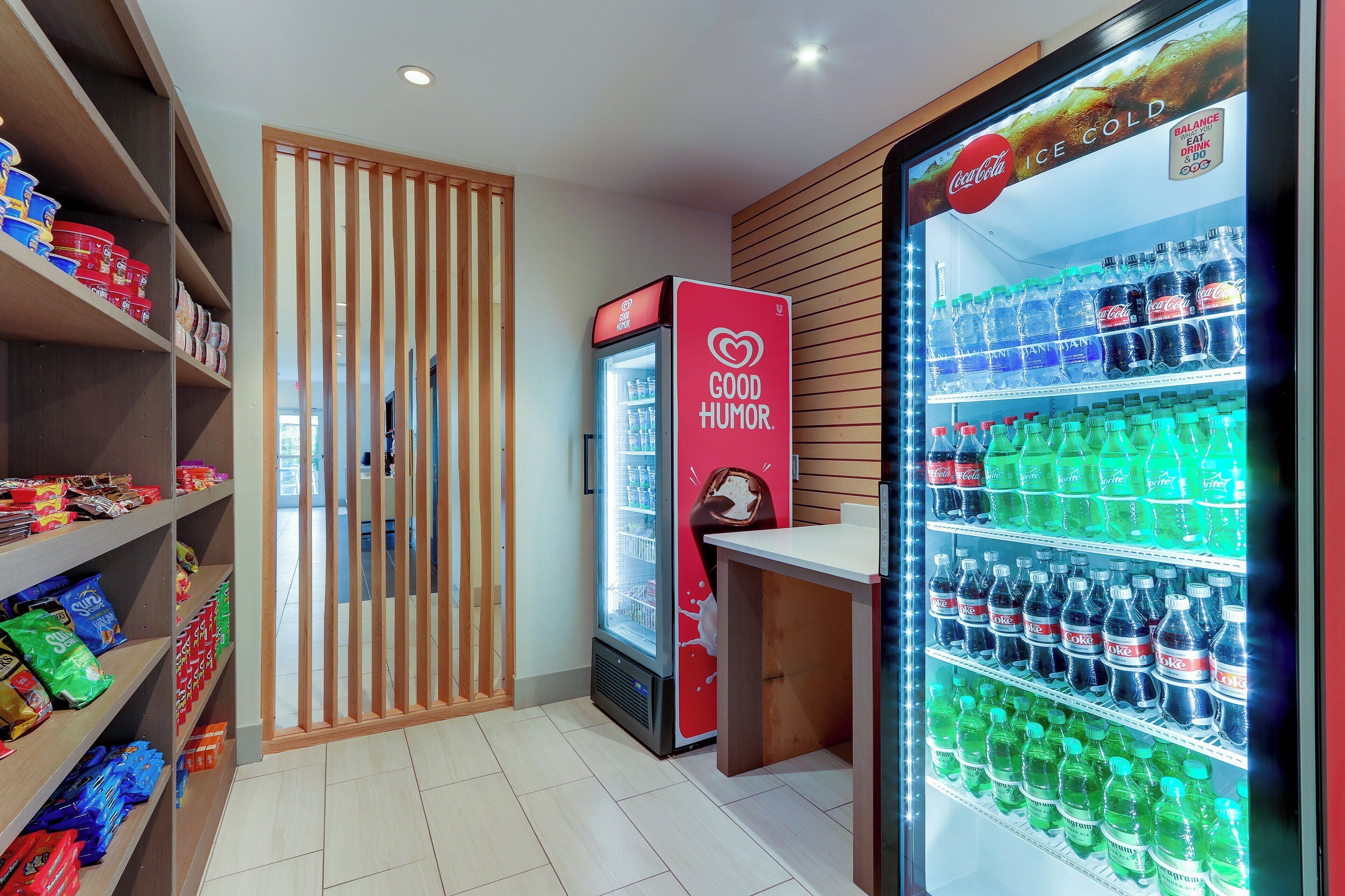 Zona de venta con diversos aperitivos y bebidas, que incluye un refrigerador de Coca-Cola y un expositor refrigerado de helados Good Humor.