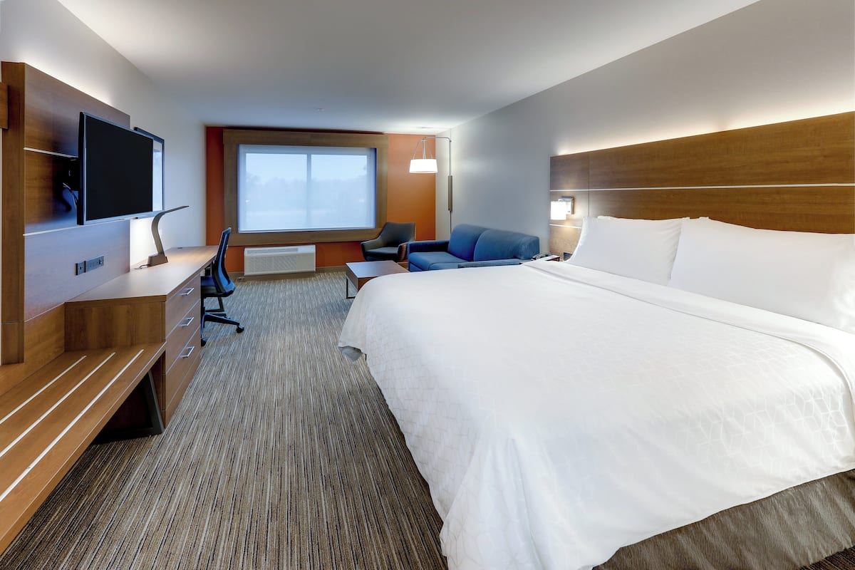 Habitación de hotel con una cama grande, un escritorio, un televisor de pantalla plana, una silla y una ventana con vistas.