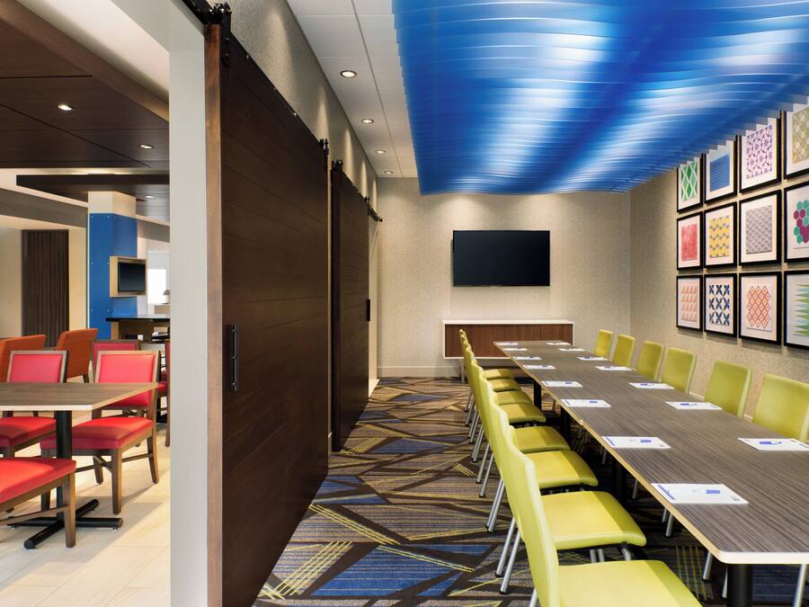 A conference room with a long table, yellow chairs, and a blue patterned ceiling.