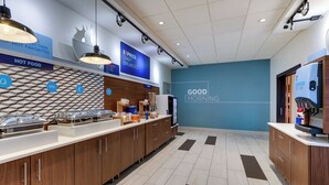 A modern breakfast area with a blue wall, wooden cabinets, and a tiled floor. - Holiday Inn Express & Suites Middletown - Goshen by IHG (Middletown)