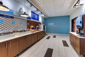 A modern breakfast area with a blue wall, wooden cabinets, and a tiled floor. - Holiday Inn Express & Suites Middletown - Goshen by IHG (Middletown)