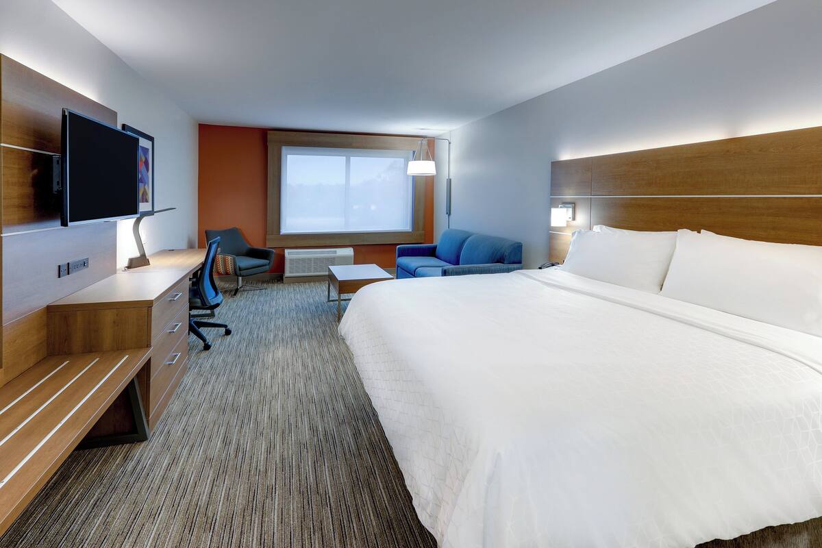 Habitación de hotel con una cama grande, un escritorio con silla, un televisor y una ventana con vistas.