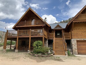 Step up to the entrance of this charming cabin, featuring a wooden door and a small staircase leading to a spacious balcony.