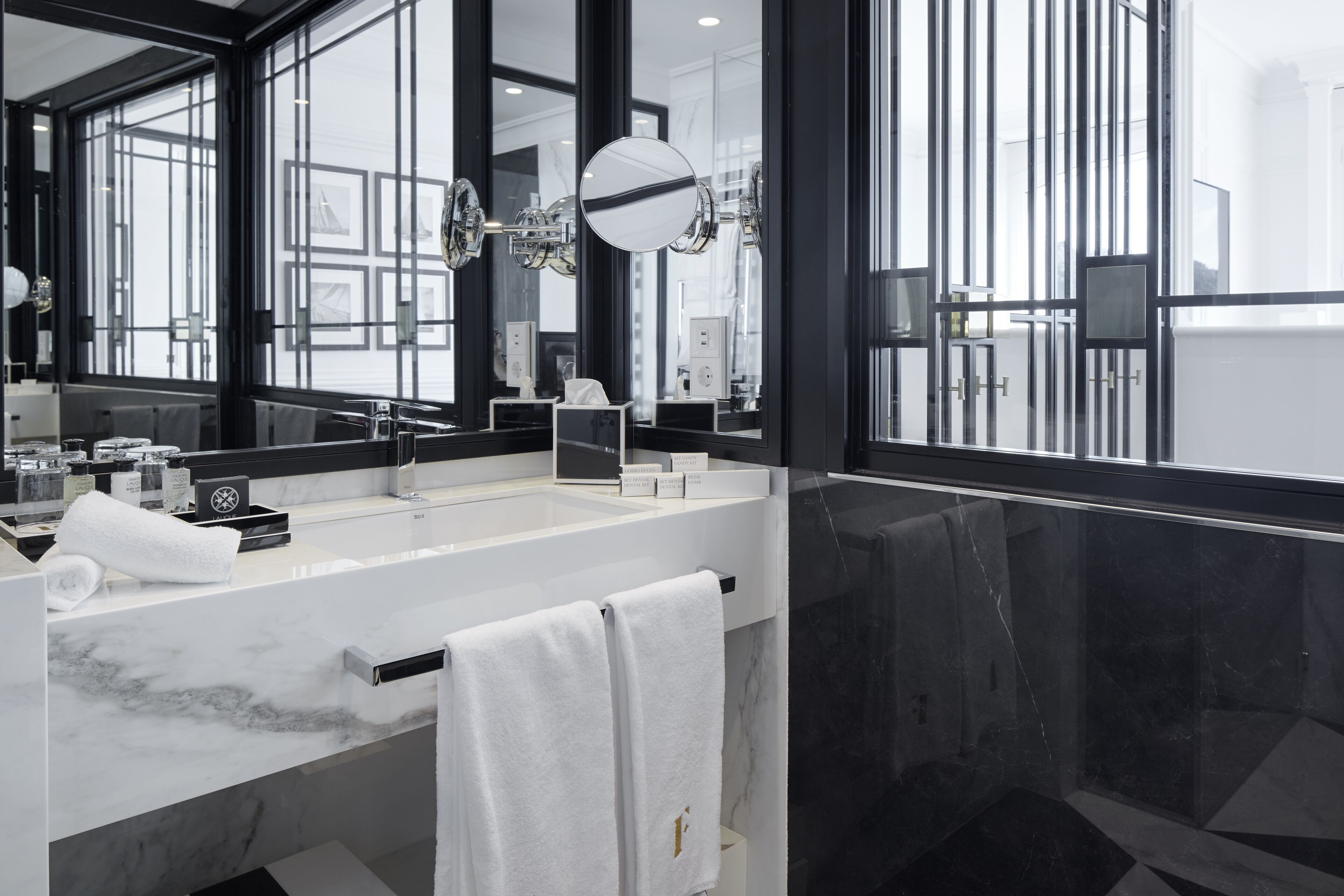 Une salle de bain moderne avec un grand miroir, un lavabo blanc et un plan de toilette en marbre noir.