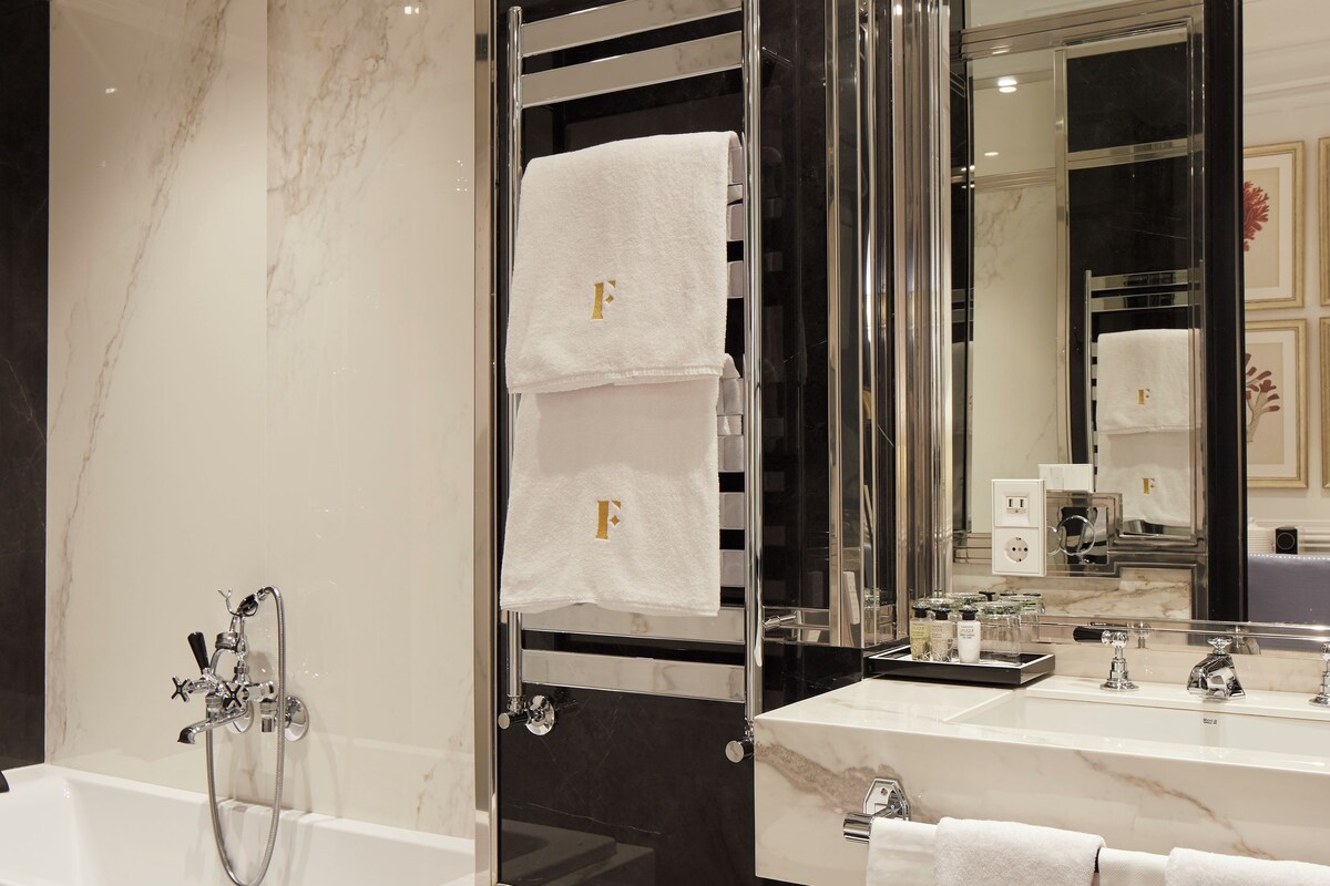 A modern bathroom with a bathtub, a large mirror, and a vanity with a sink.