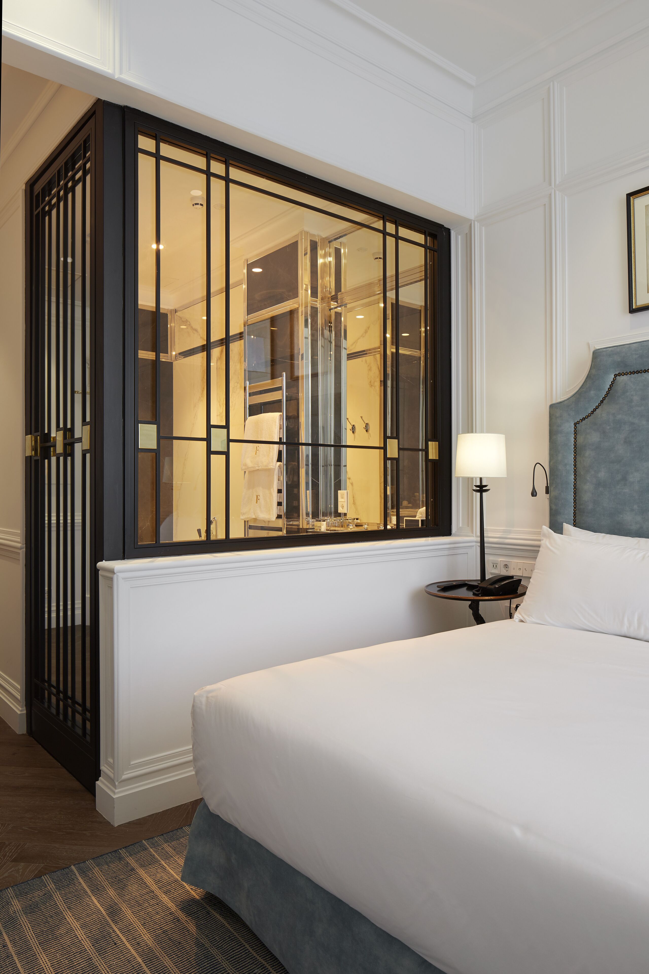 Ein Hotelzimmer mit einem großen Bett, einem Nachttisch mit Lampe und einem Schrank mit Spiegel.