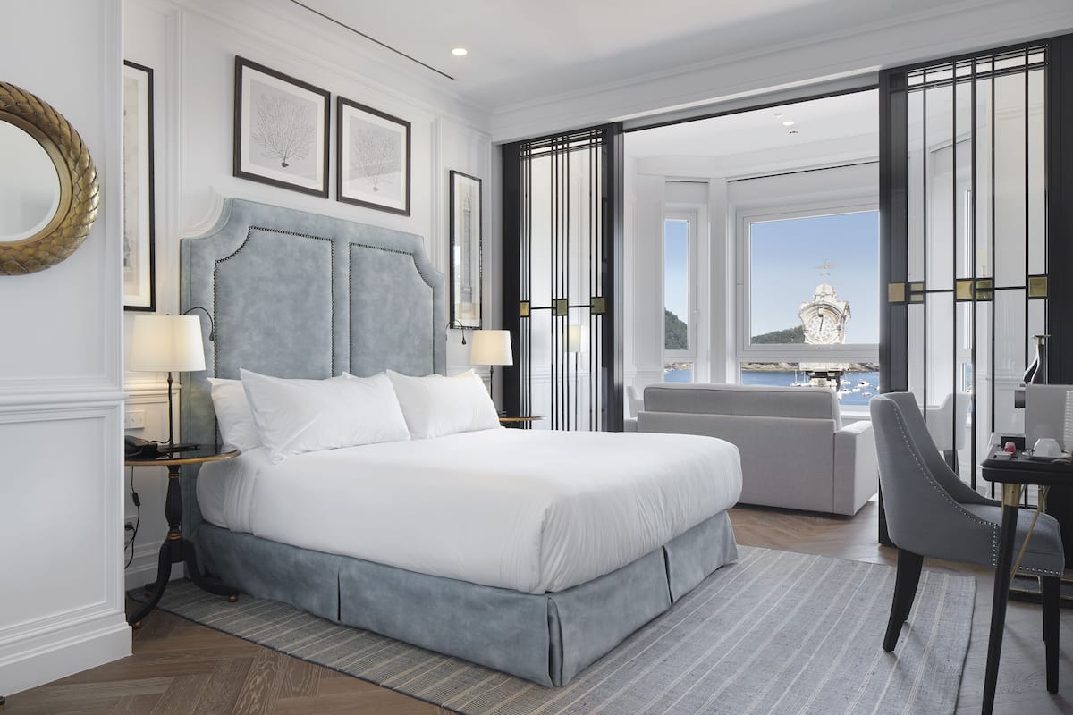 Habitación de hotel moderna con una cama grande, un escritorio y vistas a un cuerpo de agua.