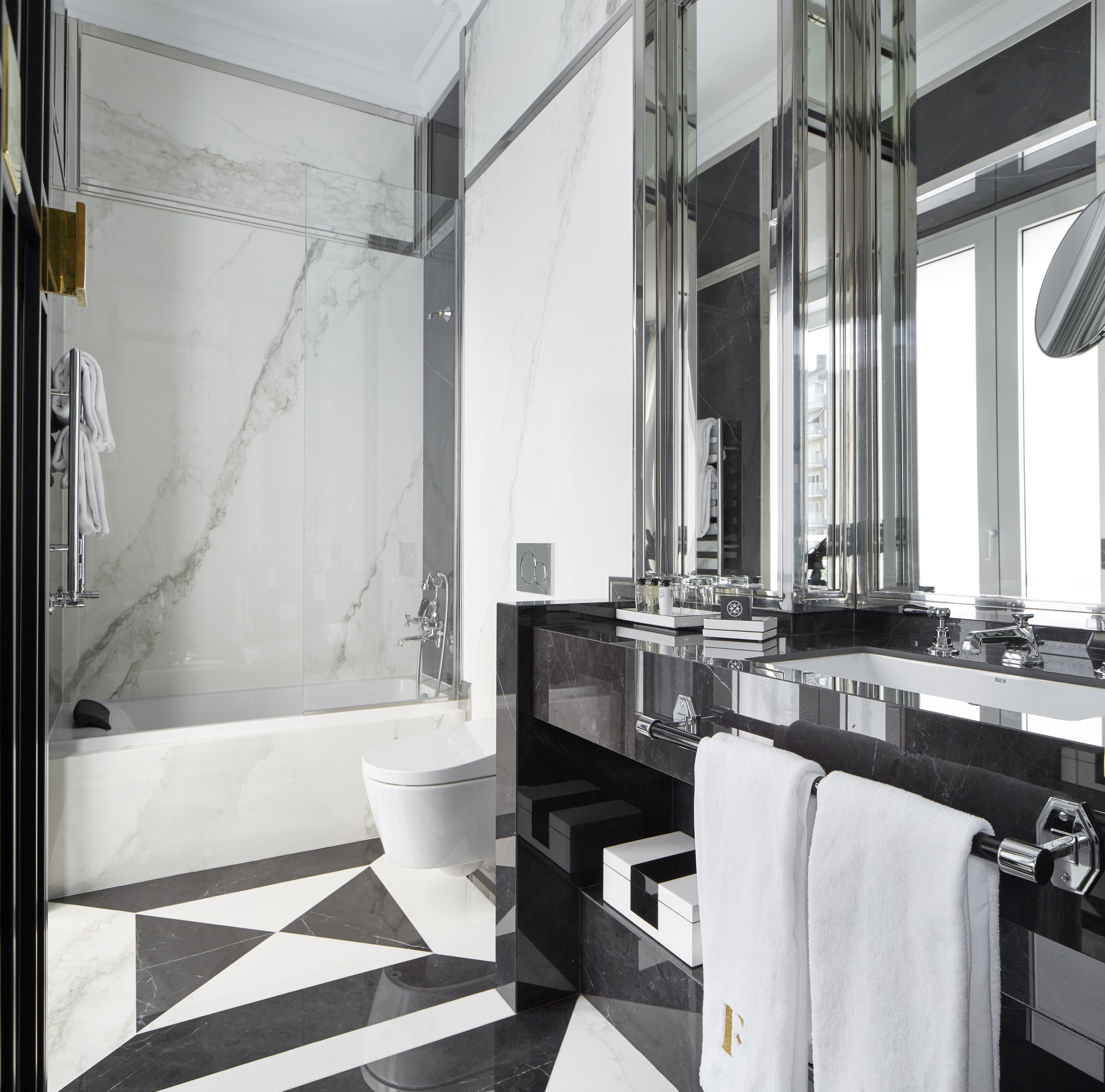 A modern bathroom with a bathtub, toilet, and a large mirror.