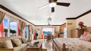 A spacious room with a large bed, a sofa, a dining table, and a view of the sea. - Flounder at Anguillitta (Blowing Point)