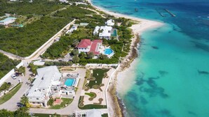 An aerial view of a coastal property with a large swimming pool, a tennis court, and a beach. - Flounder at Anguillitta (Blowing Point)