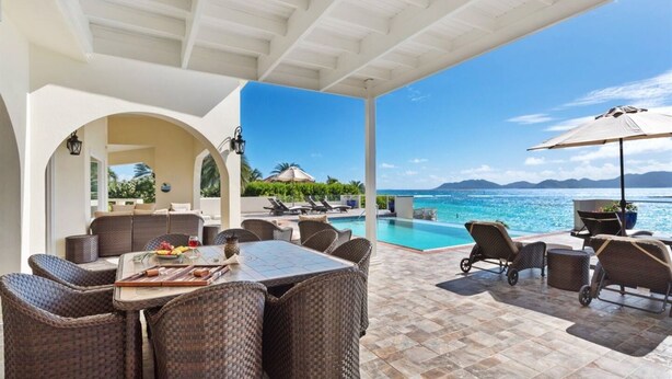 An outdoor patio with wicker furniture, a pool, and a view of the ocean. - Flounder at Anguillitta (Blowing Point)