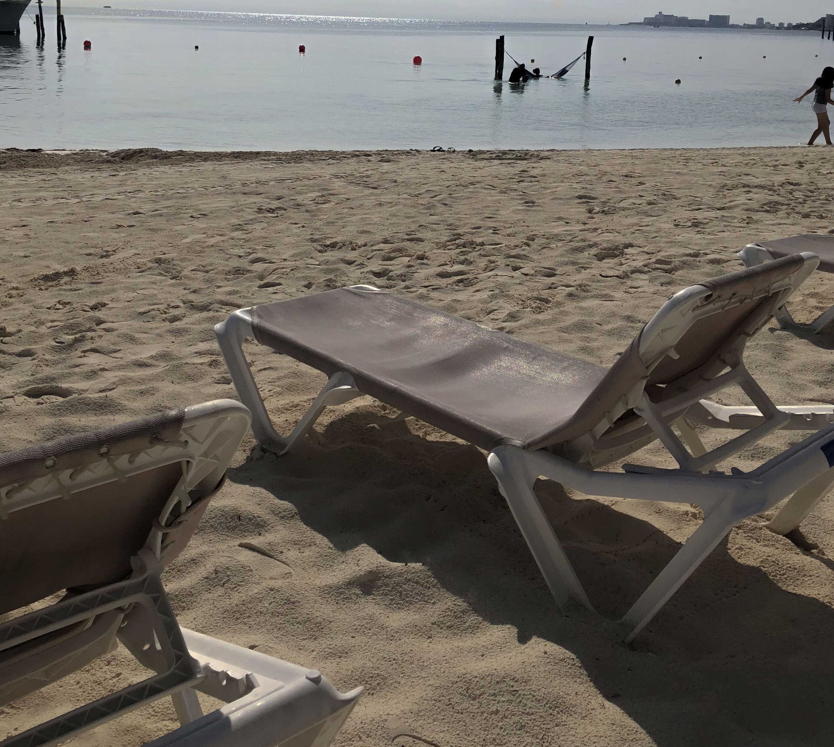 A beach with two sun loungers and a sandy shore.