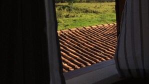A window with a view of a green field and trees, a wooden ceiling, and curtains. - Hospedaria e Restaurante Chalé da Serra (Lima Duarte)