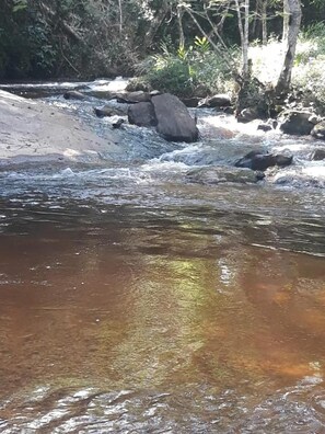 A river with clear water, surrounded by rocks and trees.