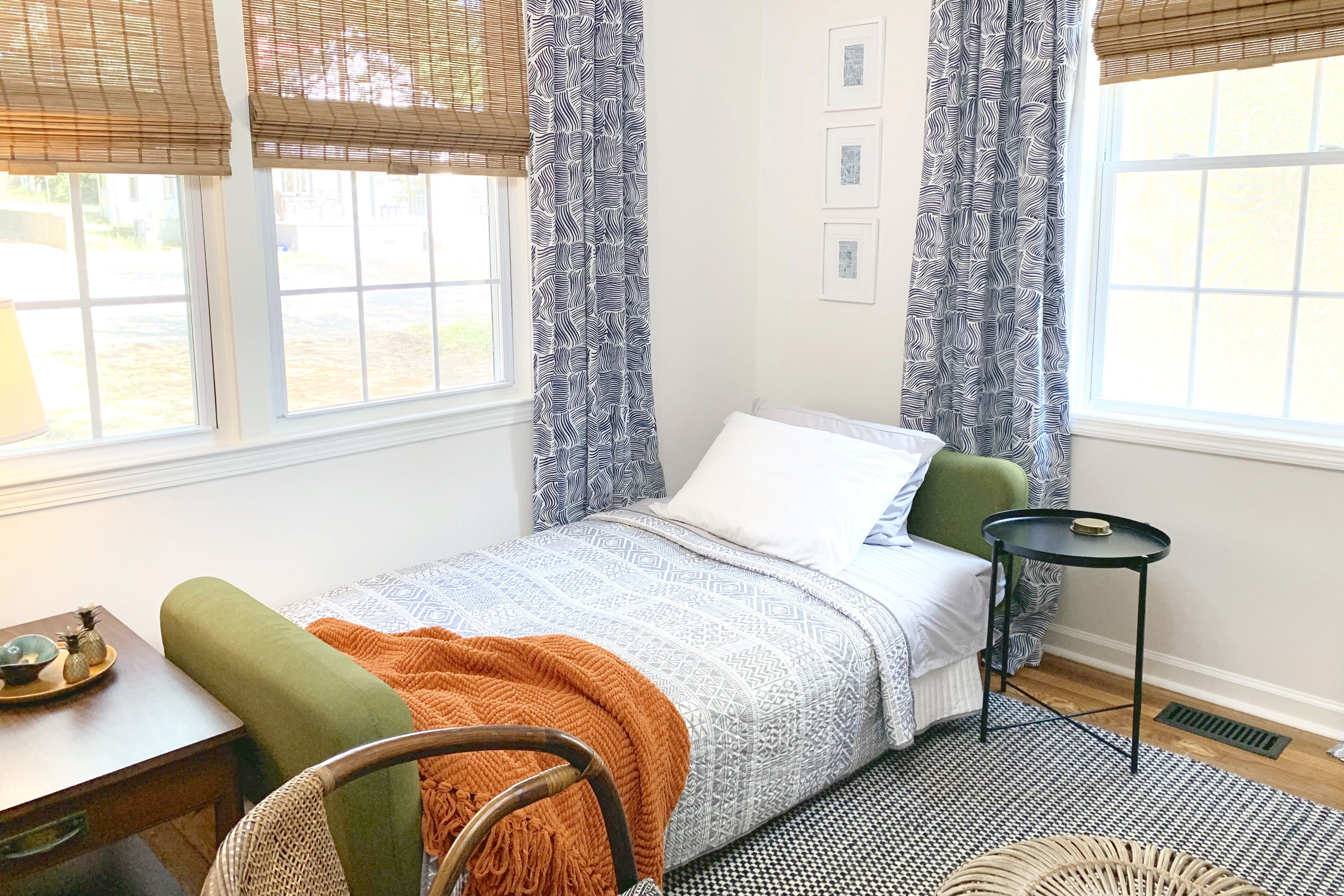Une chambre à coucher avec un lit, une chaise, une table et une fenêtre avec des rideaux.