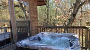 A hot tub on a wooden deck with a view of trees.