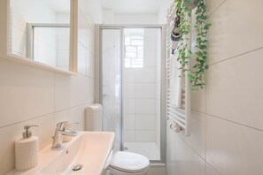 Une salle de bain avec un lavabo blanc, des toilettes et une cabine de douche en verre.