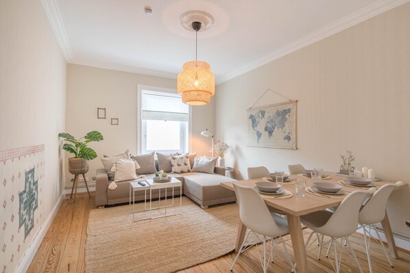 Un salon moderne avec un coin repas, doté d’une grande fenêtre, d’un luminaire suspendu et d’une carte du monde accrochée au mur.
