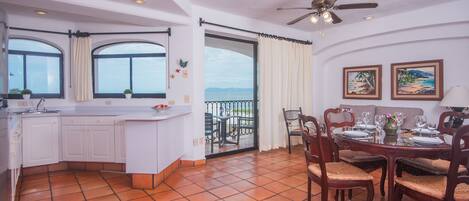 A spacious kitchen with a dining area, large windows, and a balcony with a view.