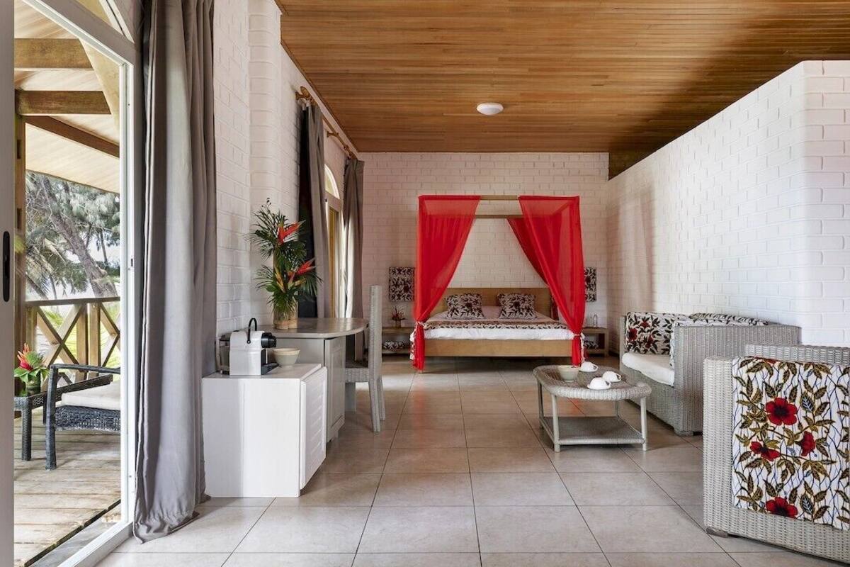 A room with a bed, a sofa, a small table, and a window.