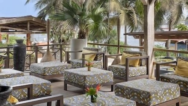 A covered outdoor seating area with cushioned benches and hanging wicker lamps.