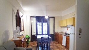 Een compact woongedeelte met een eethoek, kitchenette en een bank.